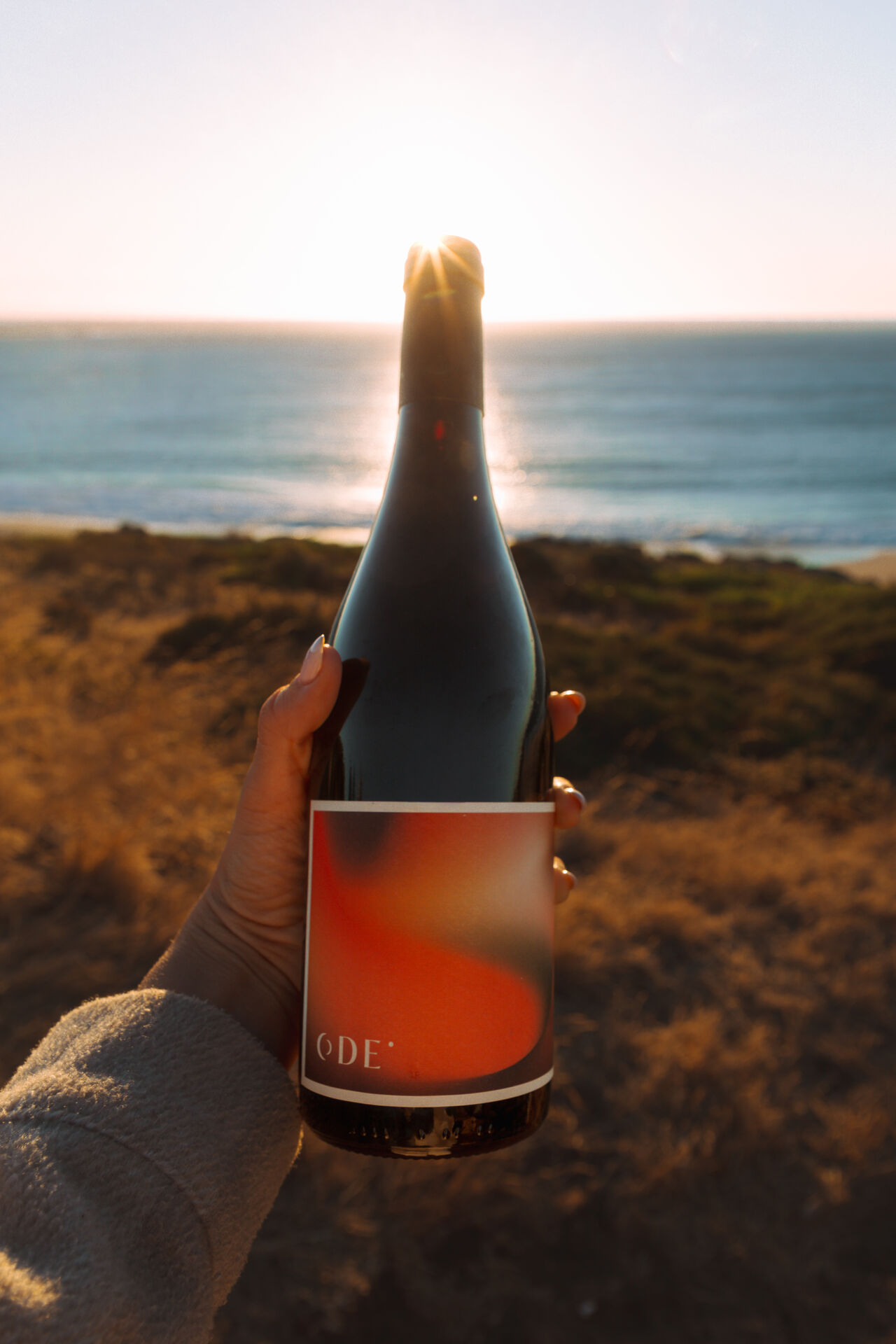 A bottle of Ode wine against a Tejo sunset.