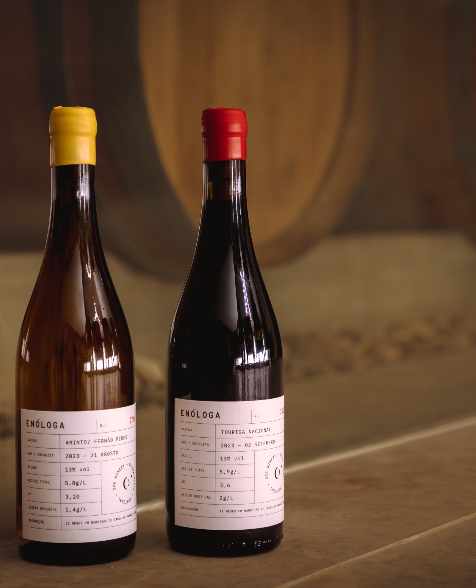 Two ODE Enóloga bottles against a rustic wooden door.